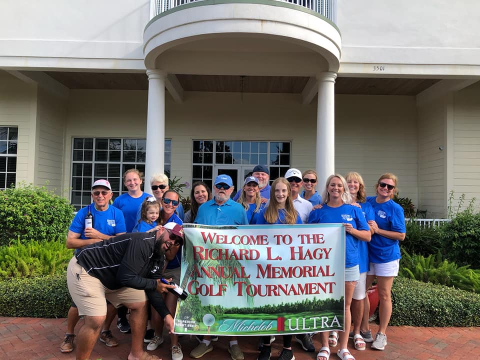 People holding the golf tournament banner
