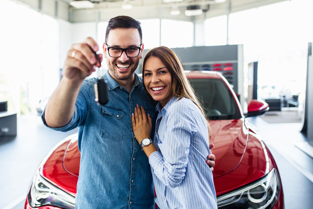 Man and woman with car keys to their new car